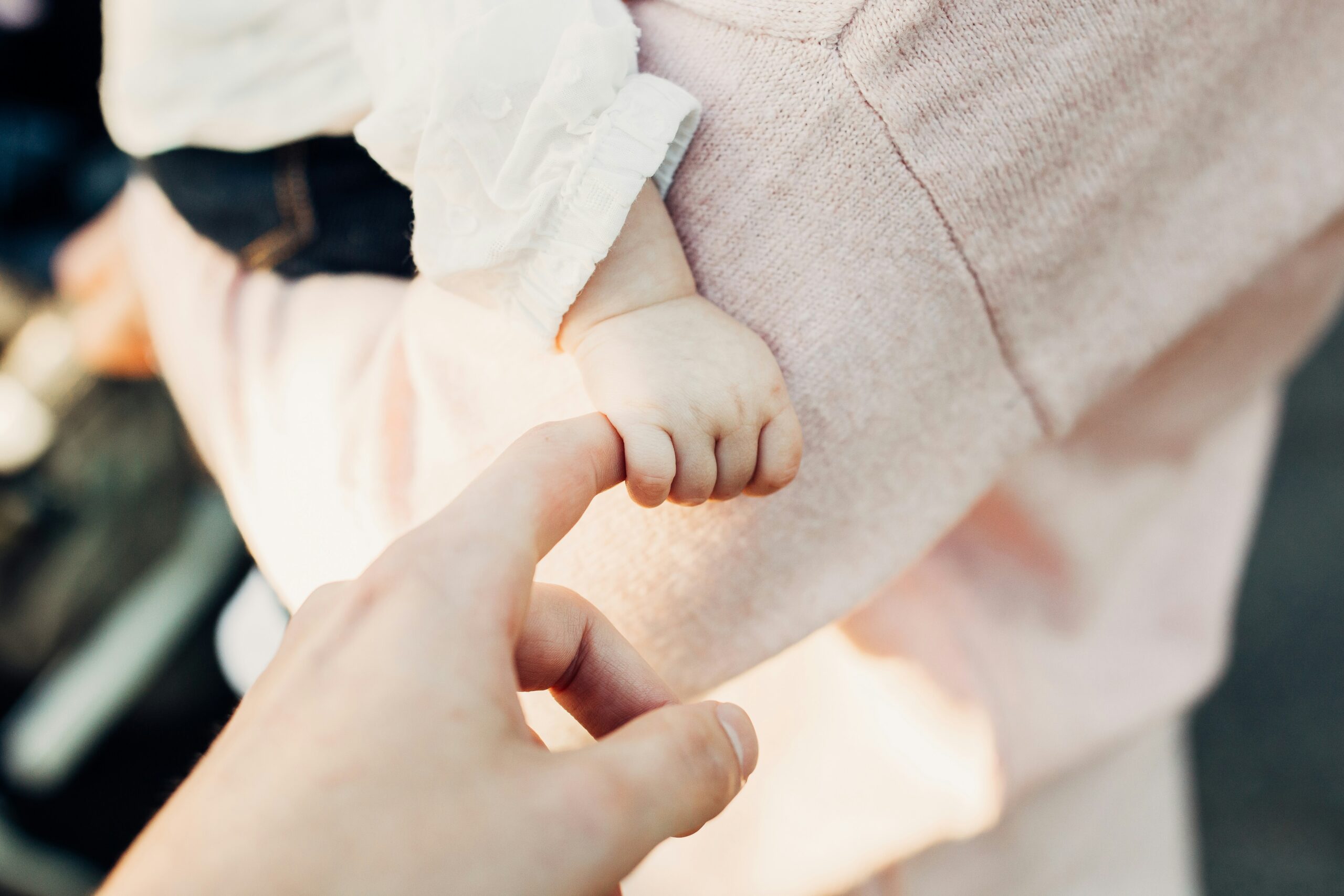 joshua-reddekopp-qLFJKFBppPM-unsplash Babyhand hält einen Finger bei einer Freien Taufe